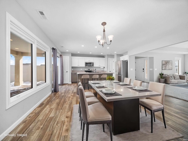 dining area with recessed lighting, visible vents, an inviting chandelier, light wood-type flooring, and baseboards