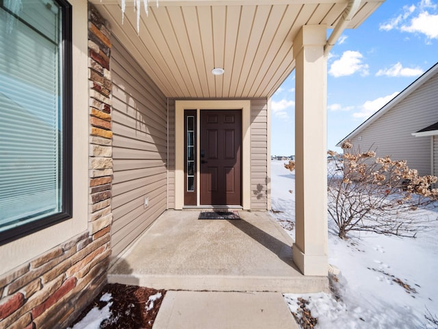 snow covered property entrance with brick siding