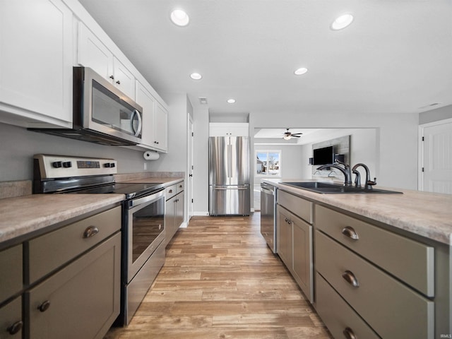 kitchen with appliances with stainless steel finishes, light wood-type flooring, gray cabinetry, and recessed lighting