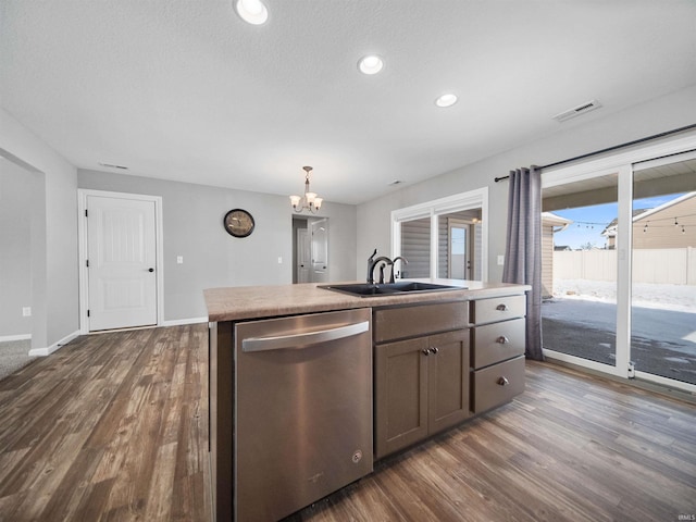 kitchen featuring visible vents, dishwasher, dark wood-style flooring, a kitchen island with sink, and a sink