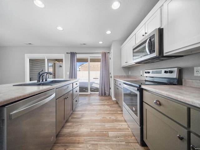 kitchen featuring recessed lighting, a sink, light countertops, appliances with stainless steel finishes, and light wood-type flooring