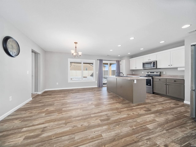 kitchen with light wood-style flooring, recessed lighting, stainless steel appliances, white cabinetry, and baseboards