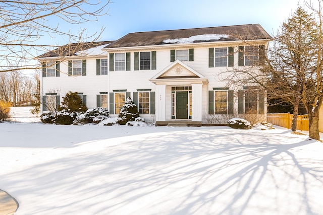 colonial-style house featuring fence