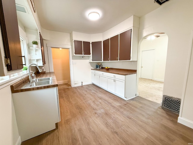 kitchen featuring arched walkways, a sink, visible vents, light wood-style floors, and open shelves