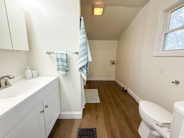 bathroom featuring visible vents, baseboards, toilet, wood finished floors, and vanity