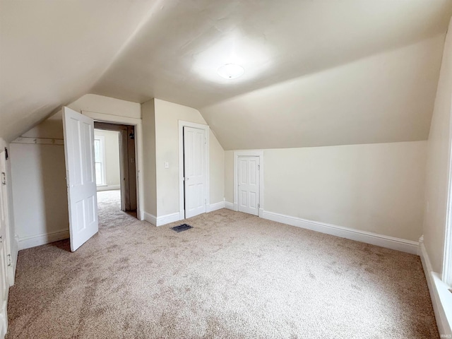 additional living space with lofted ceiling, carpet floors, visible vents, and baseboards