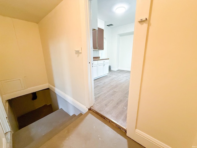 corridor featuring light wood finished floors, baseboards, and visible vents