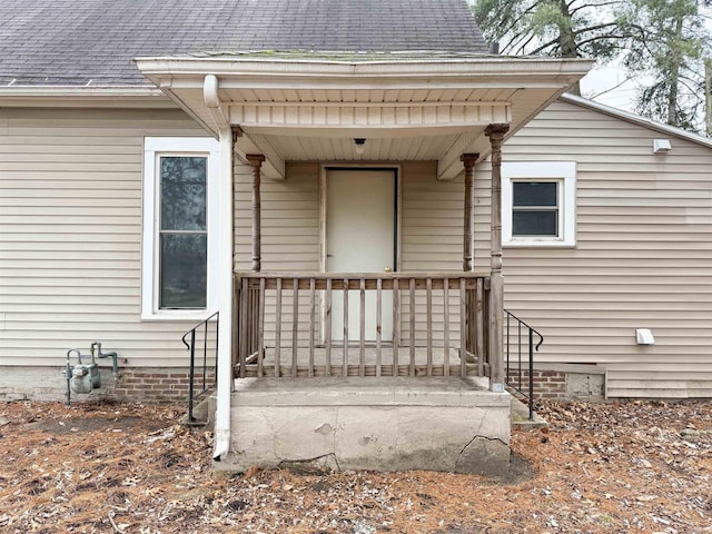 property entrance with covered porch and roof with shingles