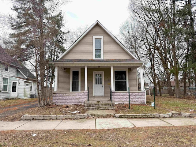 bungalow featuring covered porch, central AC unit, and roof with shingles