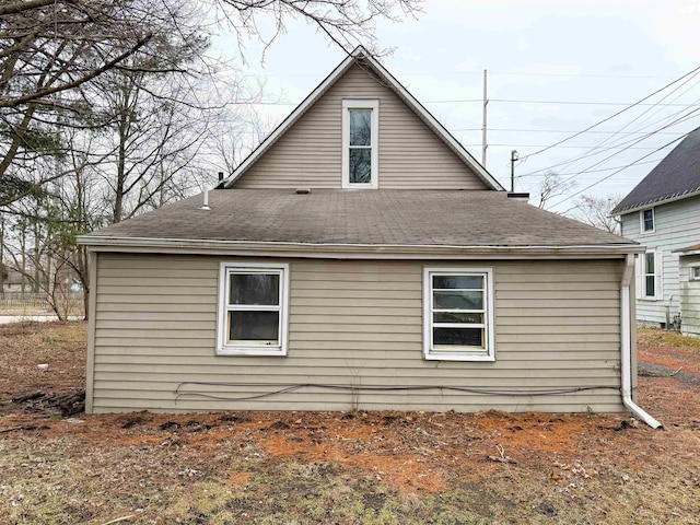 rear view of house with roof with shingles