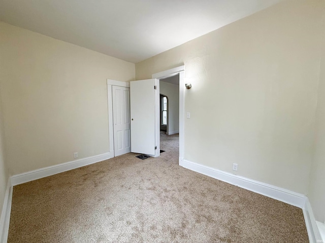 unfurnished room featuring light carpet and baseboards