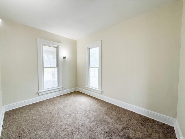 unfurnished room featuring carpet and baseboards