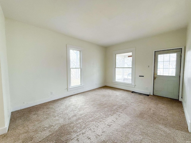 empty room with baseboards, plenty of natural light, and light colored carpet