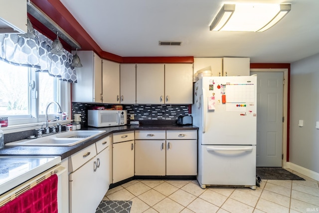 kitchen featuring white appliances, tasteful backsplash, visible vents, dark countertops, and a sink