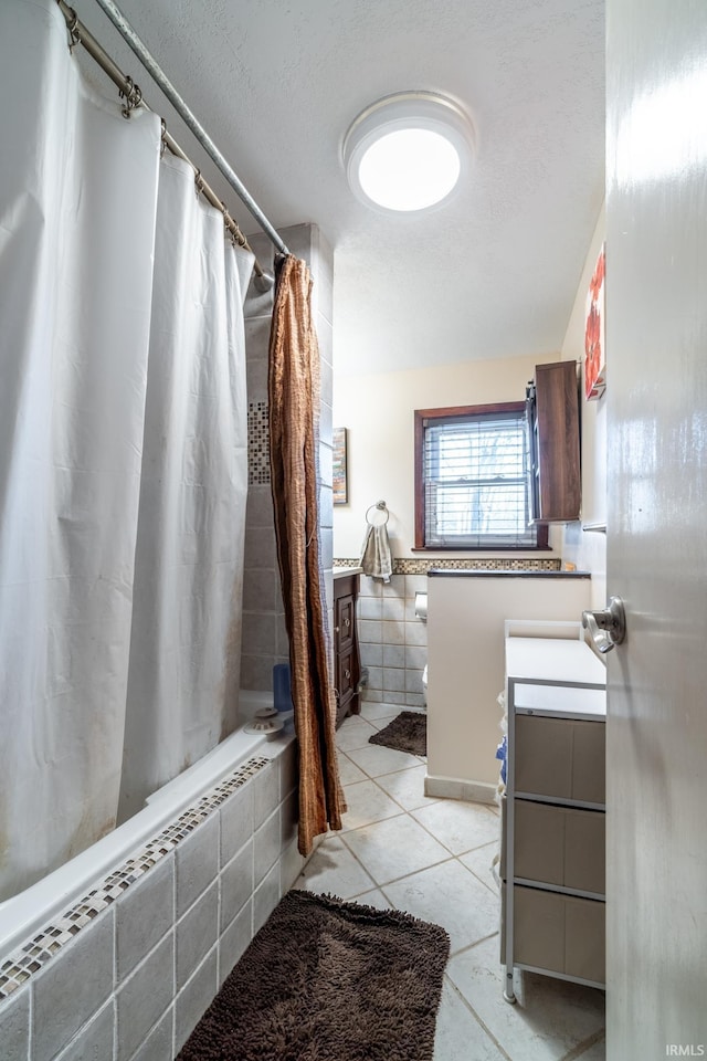 full bathroom with a textured ceiling, tile walls, vanity, tiled shower / bath, and tile patterned floors