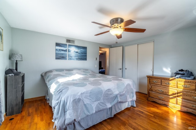 bedroom with ceiling fan, a closet, visible vents, and wood finished floors