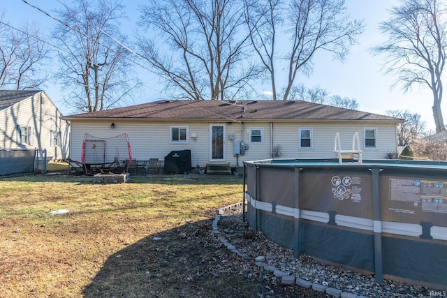 back of house with entry steps, an outdoor pool, and a yard