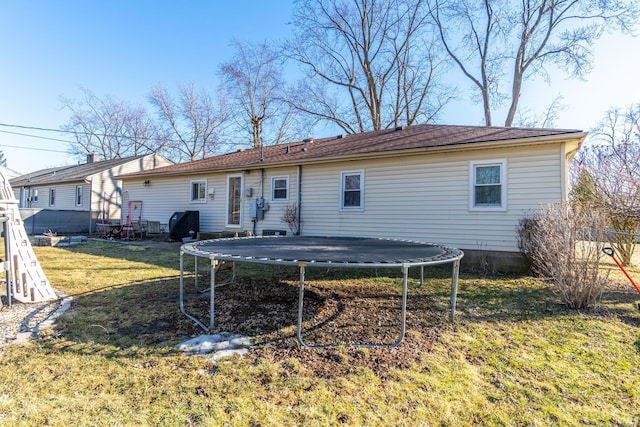 rear view of house featuring a trampoline and a lawn