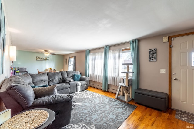 living area featuring ceiling fan, baseboard heating, and wood finished floors