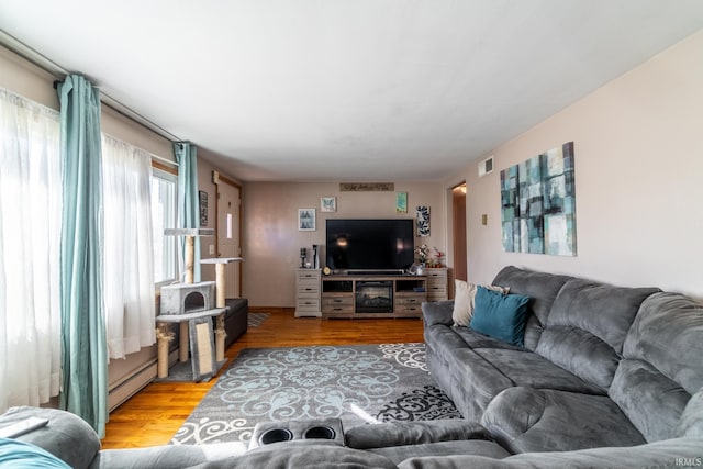 living area featuring a baseboard radiator, visible vents, and light wood-style flooring