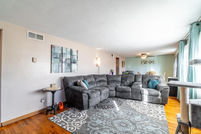 living area with baseboards, visible vents, ceiling fan, and light wood finished floors