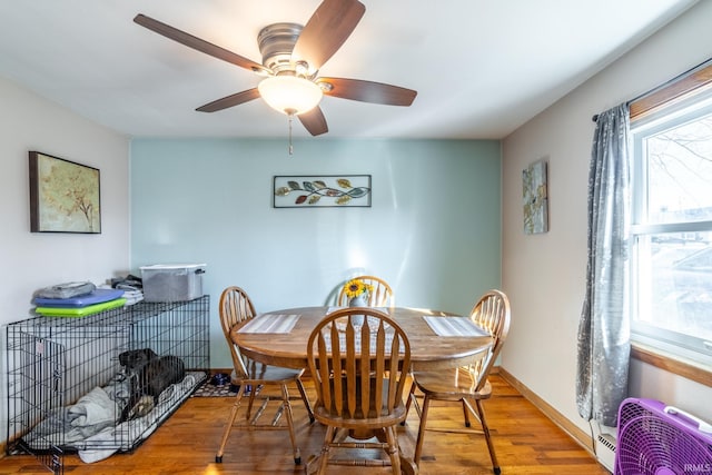 dining room featuring baseboards, ceiling fan, wood finished floors, and a healthy amount of sunlight