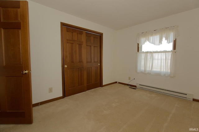 unfurnished bedroom with carpet, a closet, a baseboard radiator, and baseboards