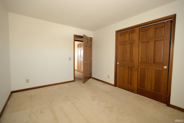 unfurnished bedroom featuring a closet, light carpet, and baseboards