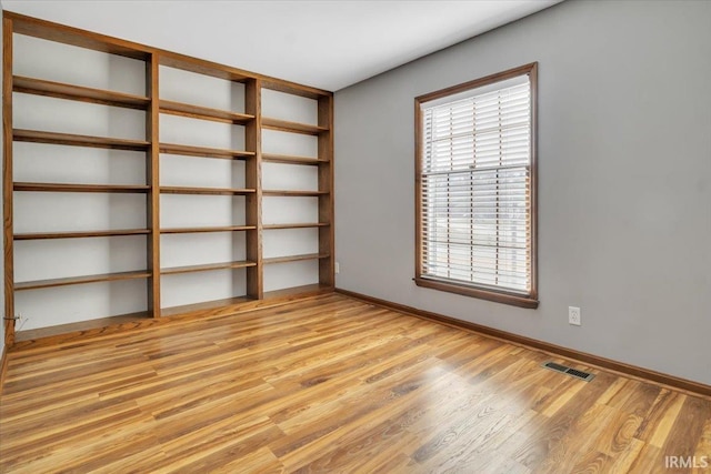 spare room with light wood-style floors, baseboards, and visible vents