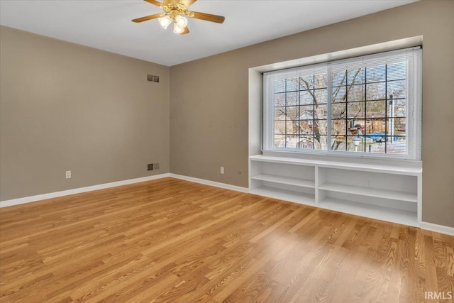 unfurnished room featuring light wood finished floors, visible vents, and baseboards