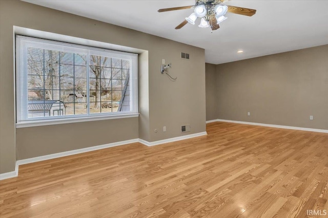 empty room featuring a ceiling fan, light wood-style flooring, visible vents, and baseboards