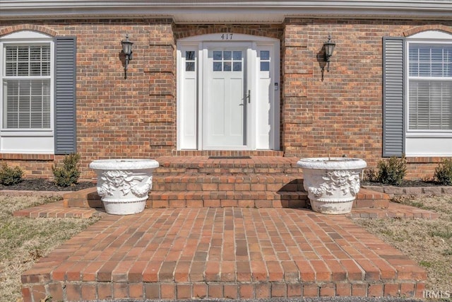 property entrance with brick siding and a patio area