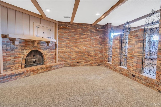 unfurnished living room featuring carpet floors, brick wall, visible vents, a brick fireplace, and beamed ceiling