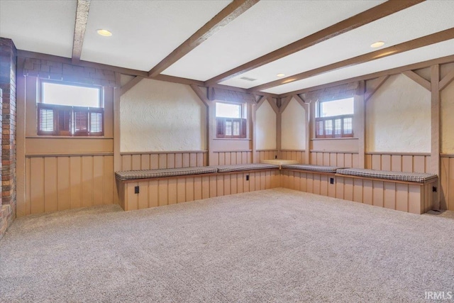 unfurnished room with carpet floors, wood walls, beamed ceiling, and wainscoting