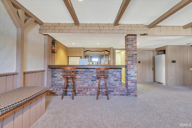 interior space featuring carpet flooring, beamed ceiling, wooden walls, and white fridge