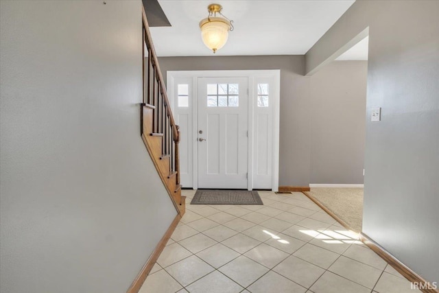 foyer entrance featuring light tile patterned floors, stairs, and baseboards