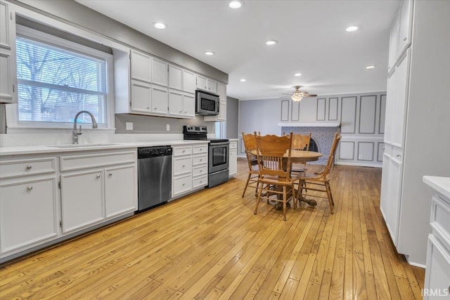 kitchen with a ceiling fan, appliances with stainless steel finishes, light countertops, light wood-style floors, and a sink