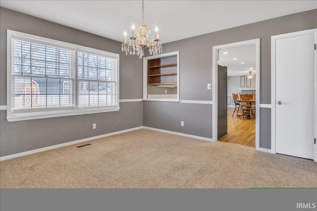 empty room featuring a notable chandelier, baseboards, visible vents, and carpet flooring