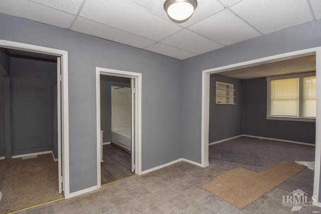 unfurnished room with a paneled ceiling and baseboards