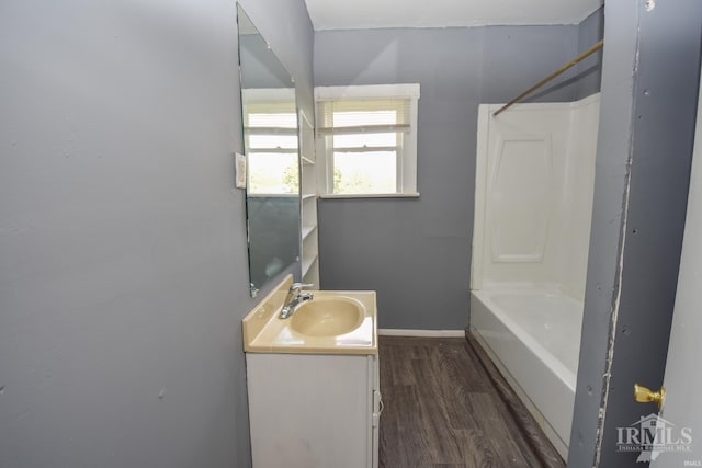 bathroom with bathtub / shower combination, vanity, baseboards, and wood finished floors