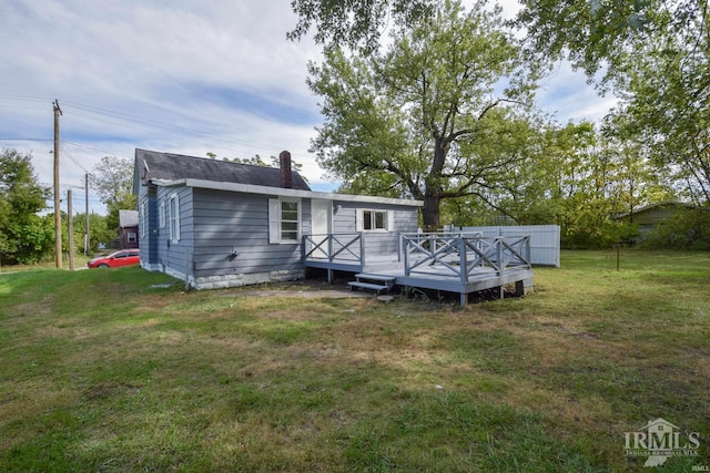 rear view of property featuring a yard and a wooden deck