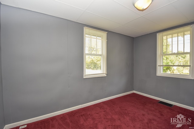 spare room with baseboards, visible vents, and dark colored carpet