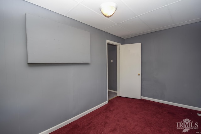 carpeted empty room with a paneled ceiling and baseboards