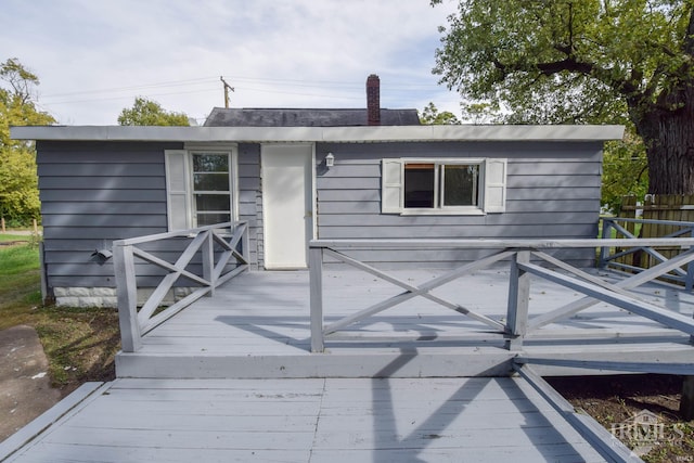 rear view of property featuring a chimney and a deck