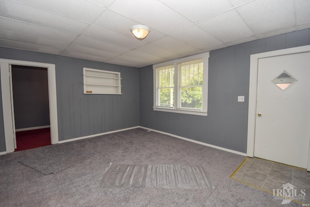 carpeted empty room featuring built in shelves, a paneled ceiling, and baseboards