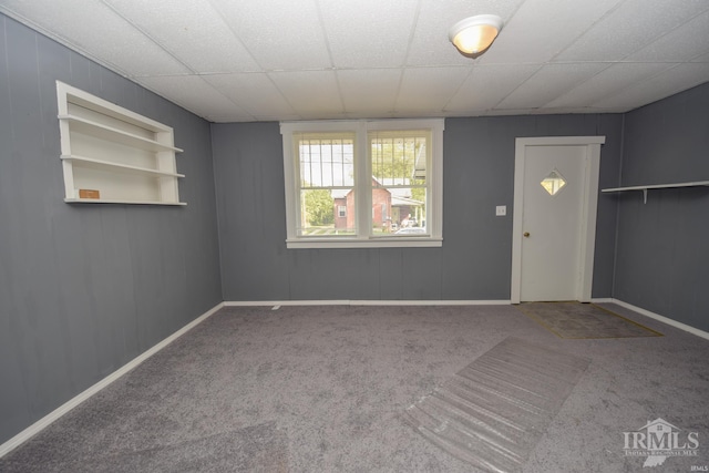 carpeted empty room with a paneled ceiling, baseboards, and built in features