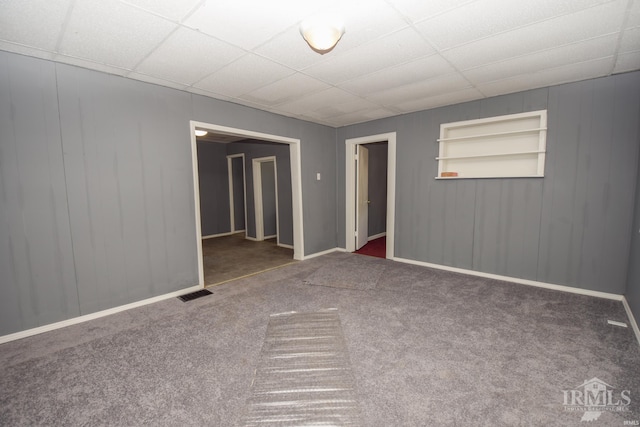 spare room with carpet, visible vents, a drop ceiling, and built in features