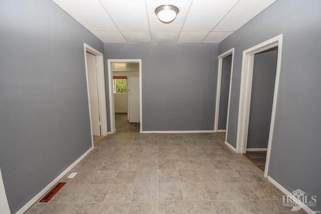 hall with a paneled ceiling and baseboards