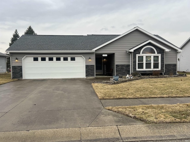 view of front facade with a garage, stone siding, a front lawn, and concrete driveway