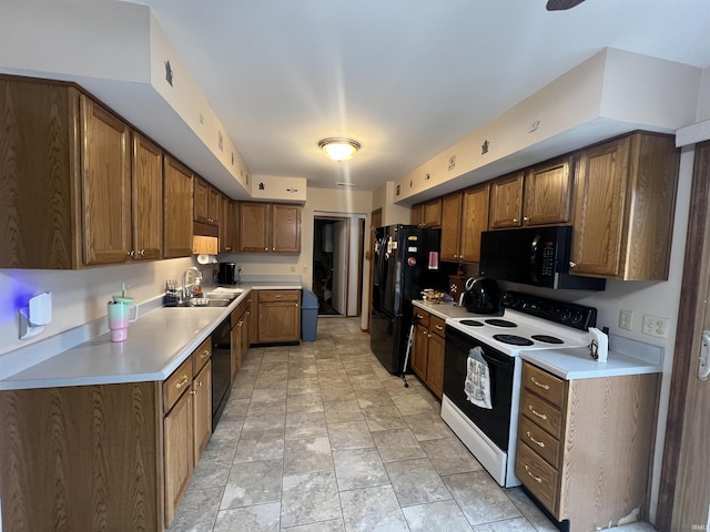 kitchen featuring black appliances, brown cabinetry, a sink, and light countertops